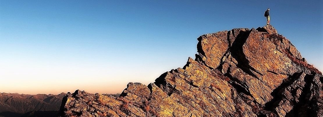 Reaching your goals and standing on top of the mountains Man standing on top of a mountain watching the sunset